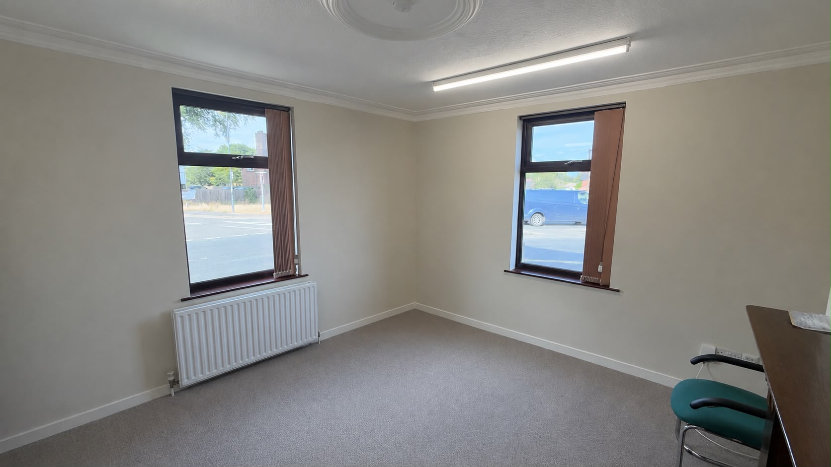 Carpeted front office with two windows and ceiling rose