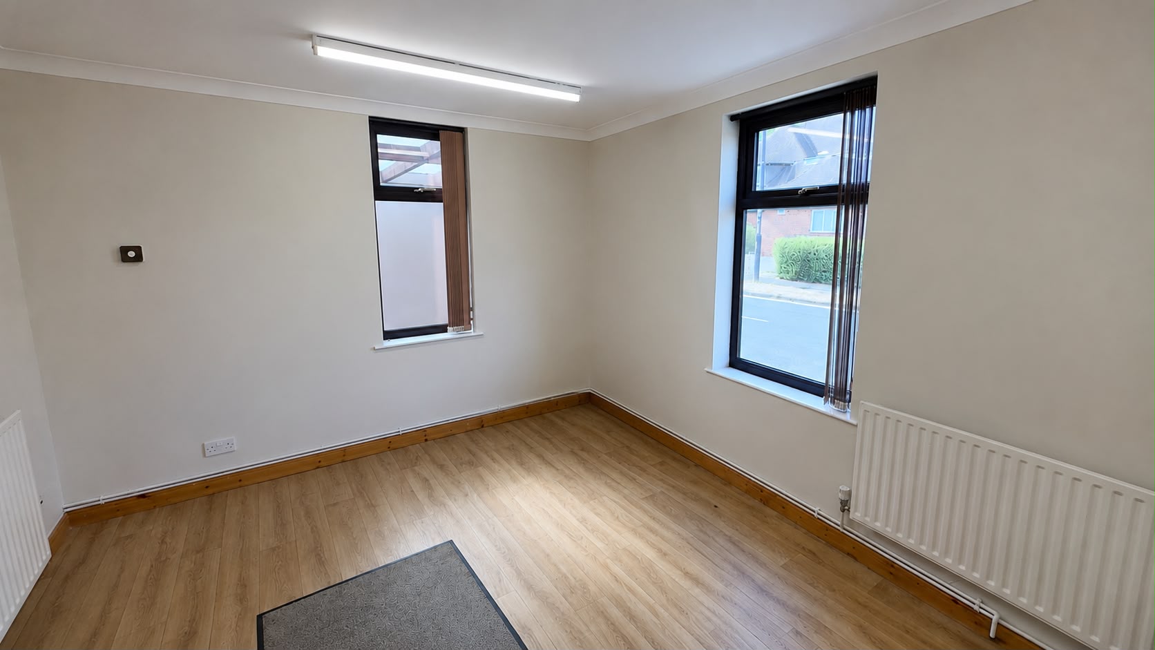 Bright ground floor office with wooden flooring and two windows
